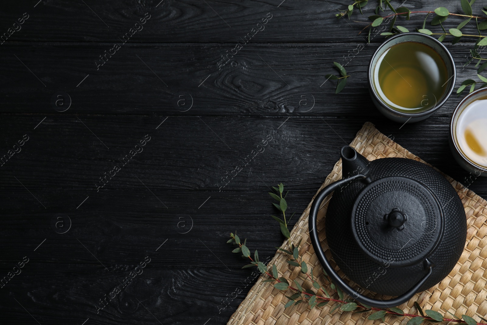 Photo of Aromatic eucalyptus tea on black wooden table, flat lay. Space for text