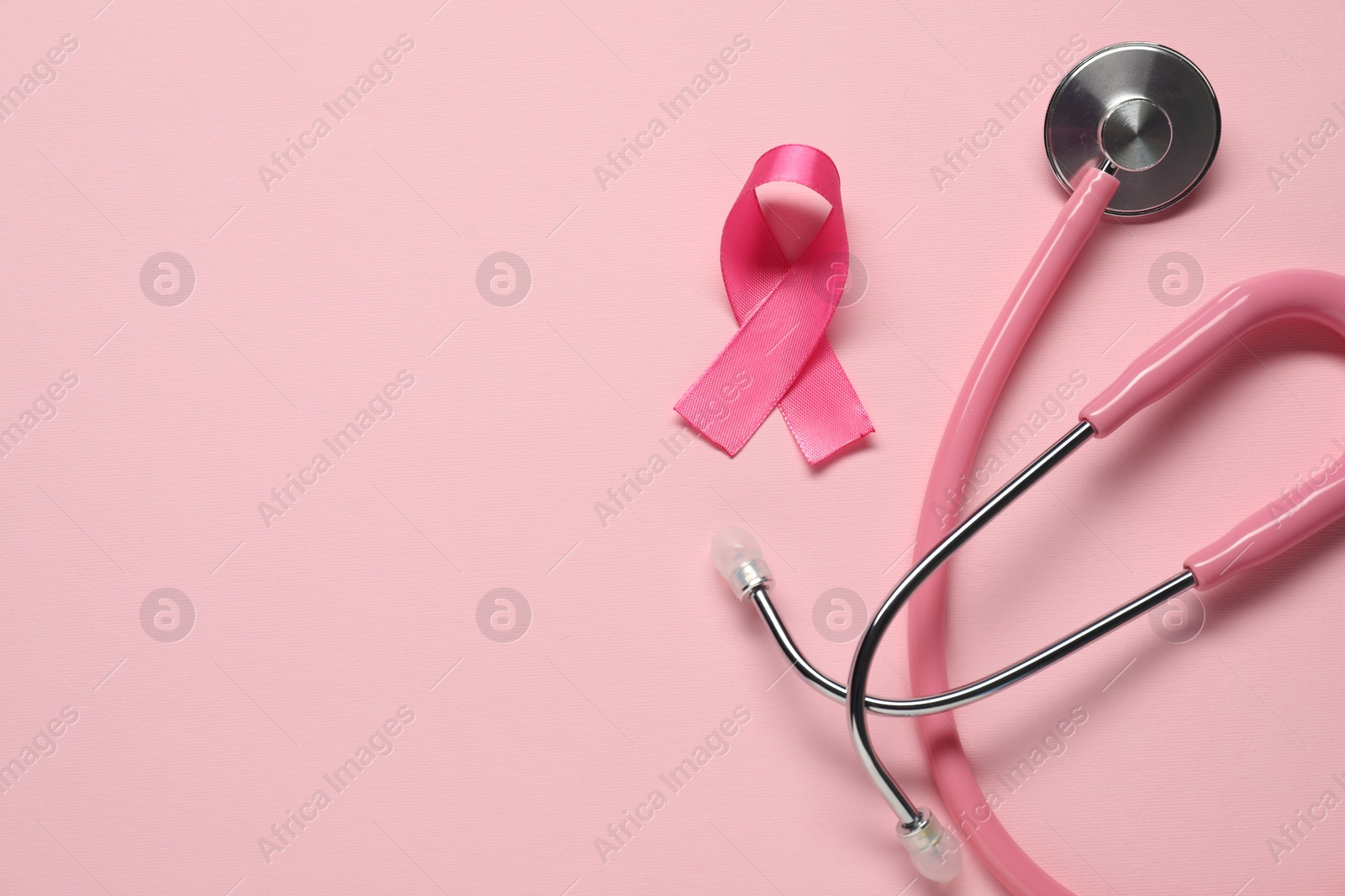 Photo of Breast cancer awareness. Pink ribbon and stethoscope on color background, flat lay. Space for text