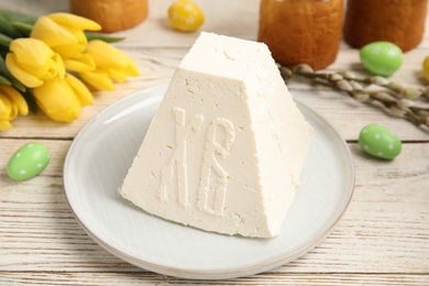 Photo of Traditional cottage cheese Easter paskha and eggs on white wooden table