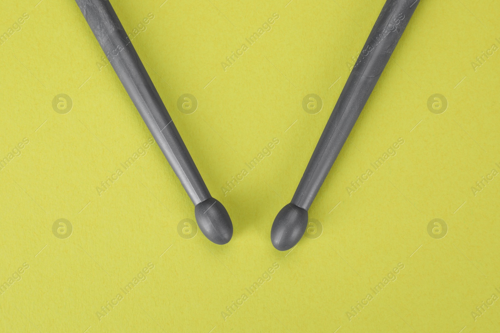 Photo of Two gray drum sticks on light green background, top view