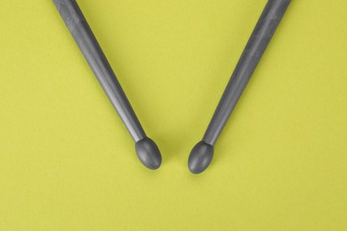 Photo of Two gray drum sticks on light green background, top view