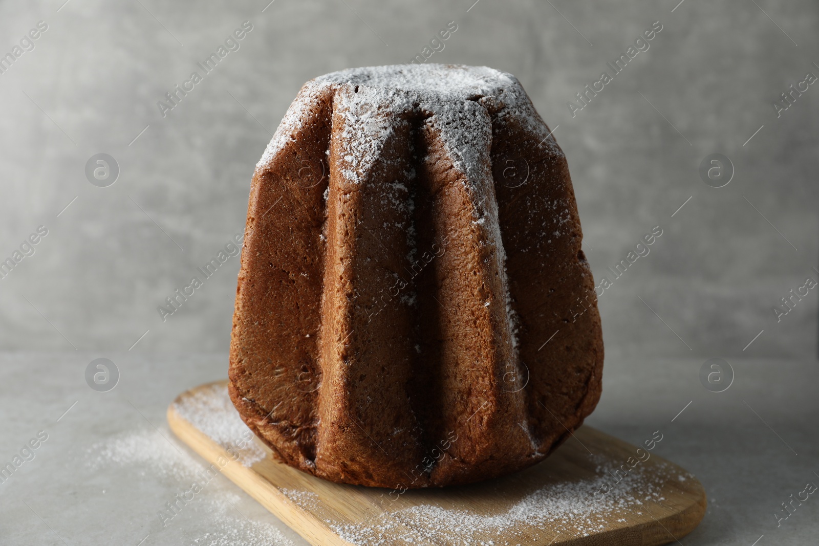 Photo of Delicious Pandoro cake decorated with powdered sugar on light grey table. Traditional Italian pastry