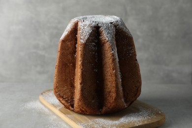 Delicious Pandoro cake decorated with powdered sugar on light grey table. Traditional Italian pastry