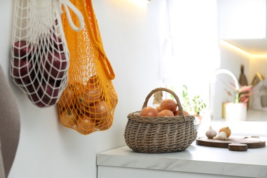 Photo of Basket with golden onions on countertop in kitchen