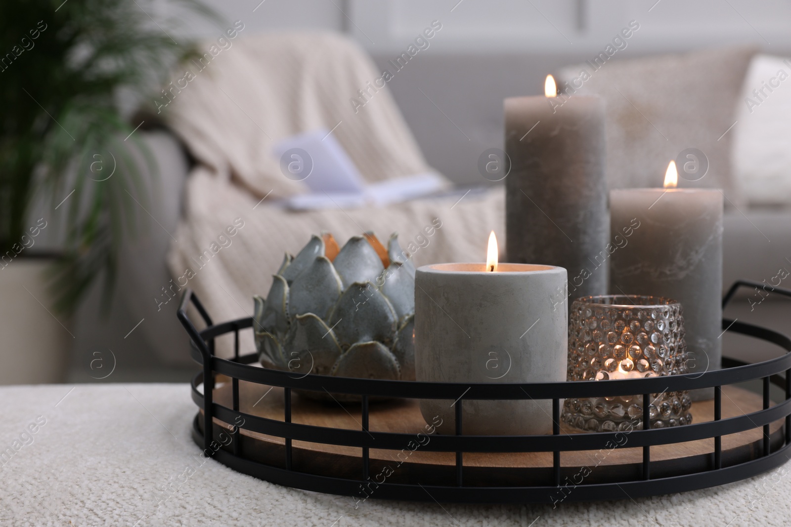 Photo of Tray with burning candles on ottoman indoors