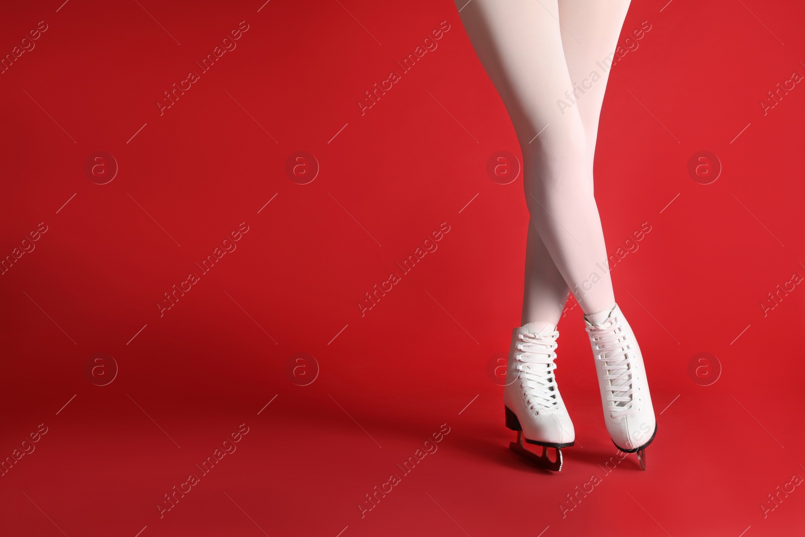 Photo of Woman in elegant white ice skates on red background, closeup of legs. Space for text