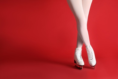 Photo of Woman in elegant white ice skates on red background, closeup of legs. Space for text