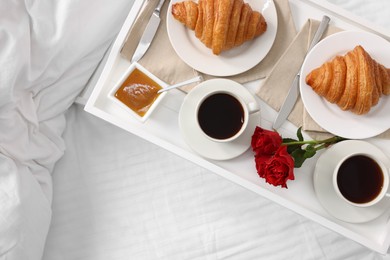 Photo of Tasty breakfast served in bed. Fresh croissants, coffee and honey on tray, top view. Space for text