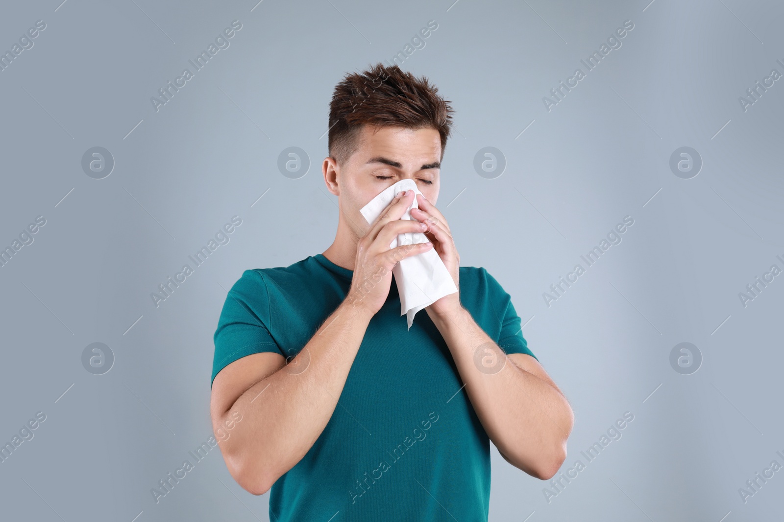 Photo of Young man suffering from allergy on grey background