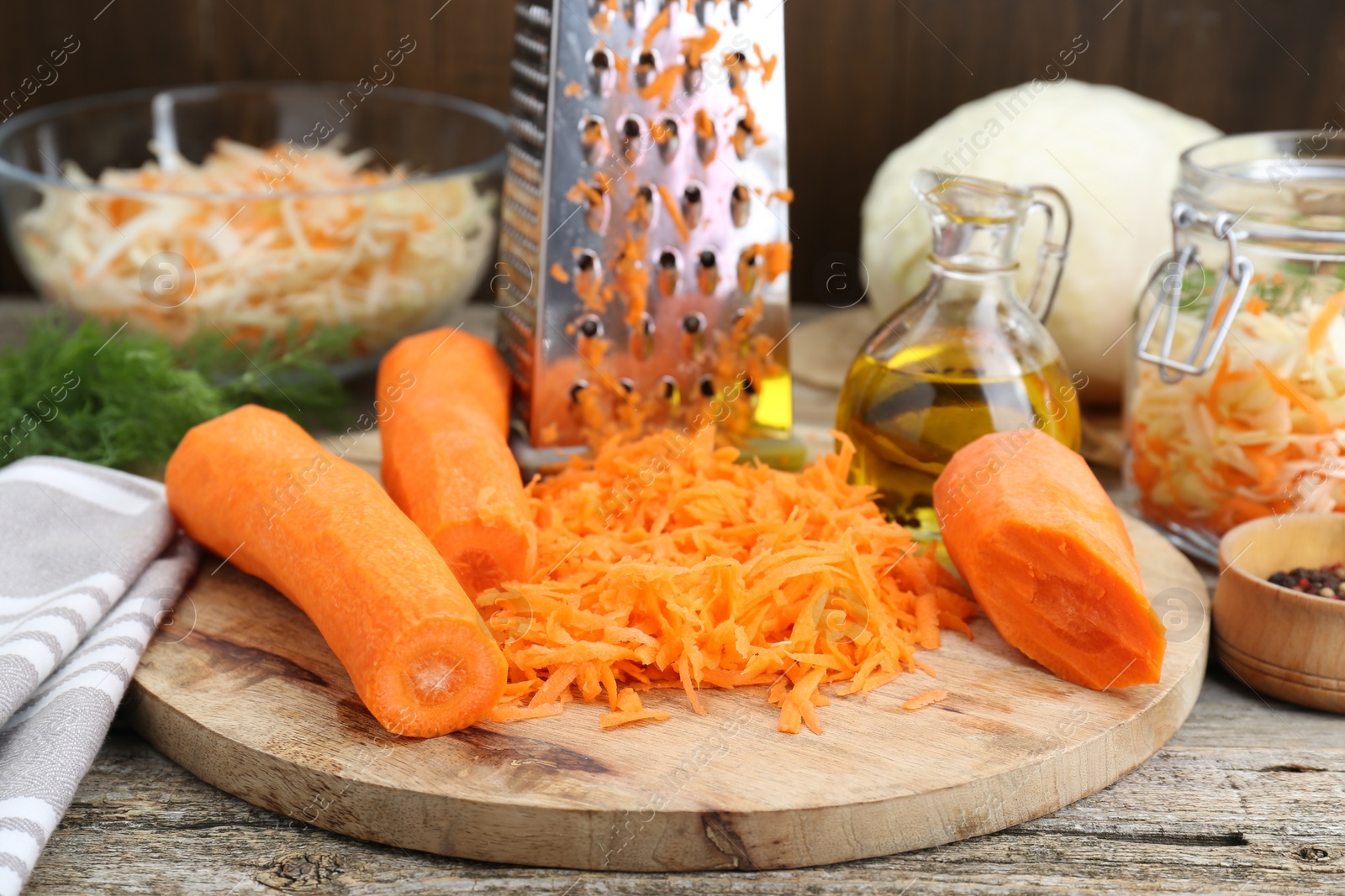 Photo of Cooking delicious sauerkraut soup. Fresh chopped carrot and ingredients on old wooden table, closeup