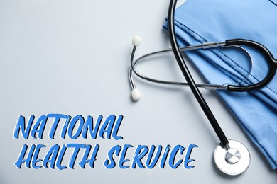 Image of National health service (NHS). Stethoscope, scrubs and text on light grey background, top view