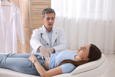 Photo of Gastroenterologist examining patient with stomach pain on couch in clinic