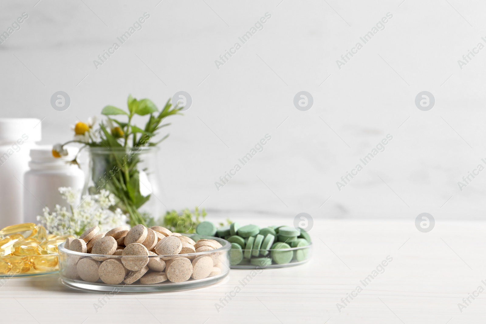 Photo of Different pills on white wooden table, space for text. Dietary supplements