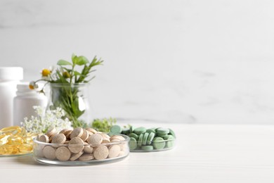 Photo of Different pills on white wooden table, space for text. Dietary supplements