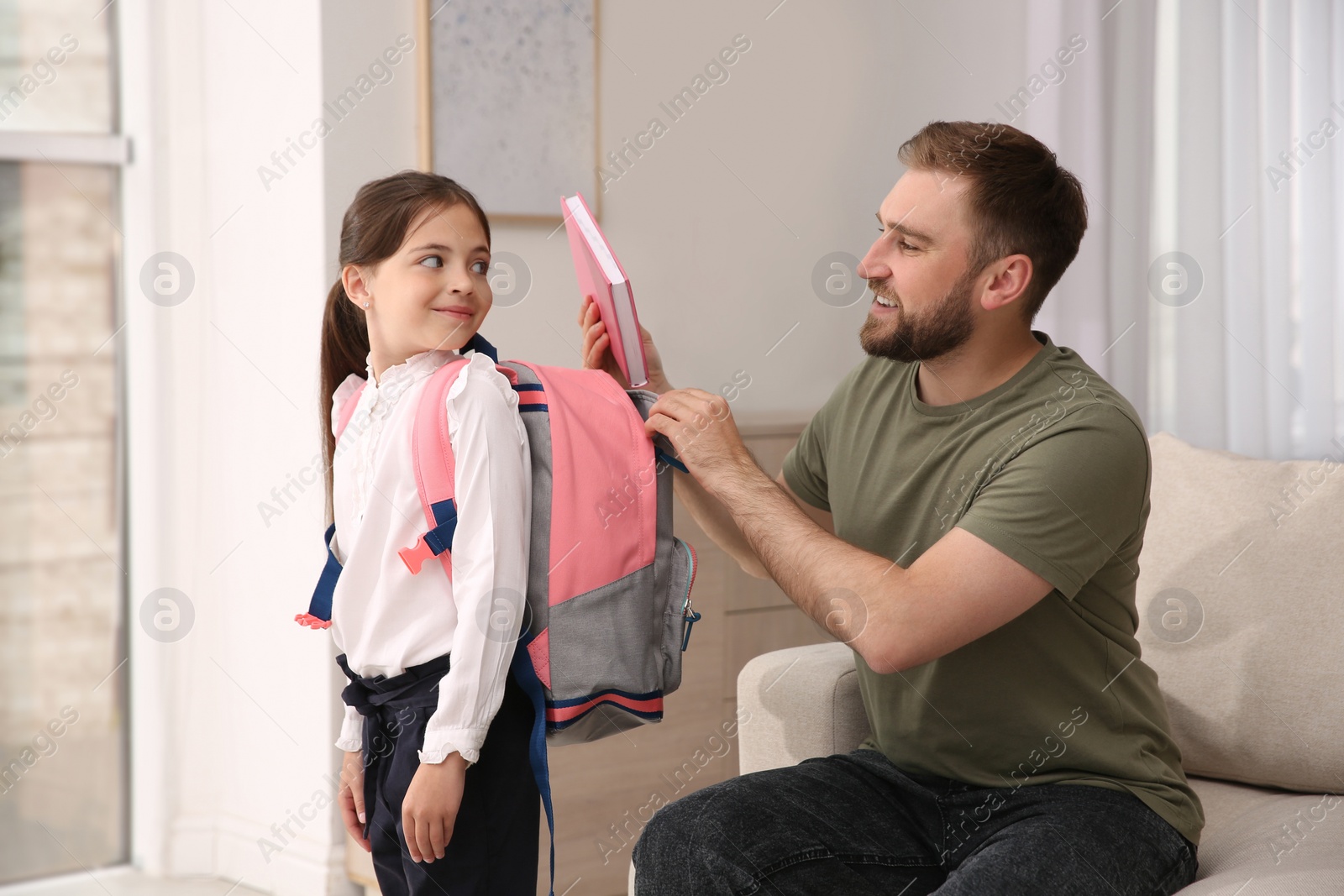 Photo of Father helping his little daughter to get ready for school indoors