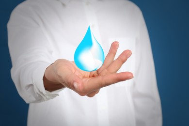 Woman holding image of water drop on blue background, closeup