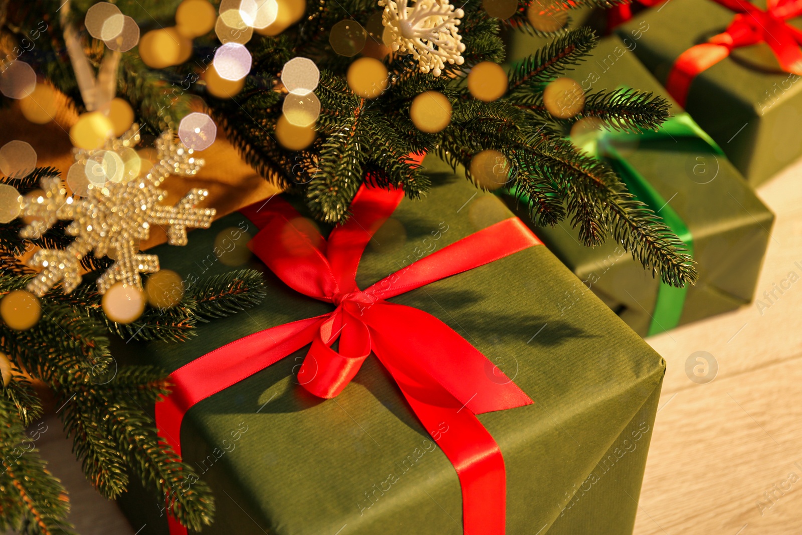 Photo of Beautifully wrapped gift boxes under Christmas tree indoors, closeup
