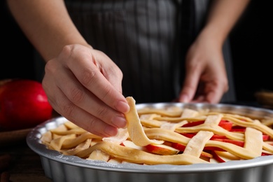 Photo of Woman making lattice top for traditional English apple pie, closeup
