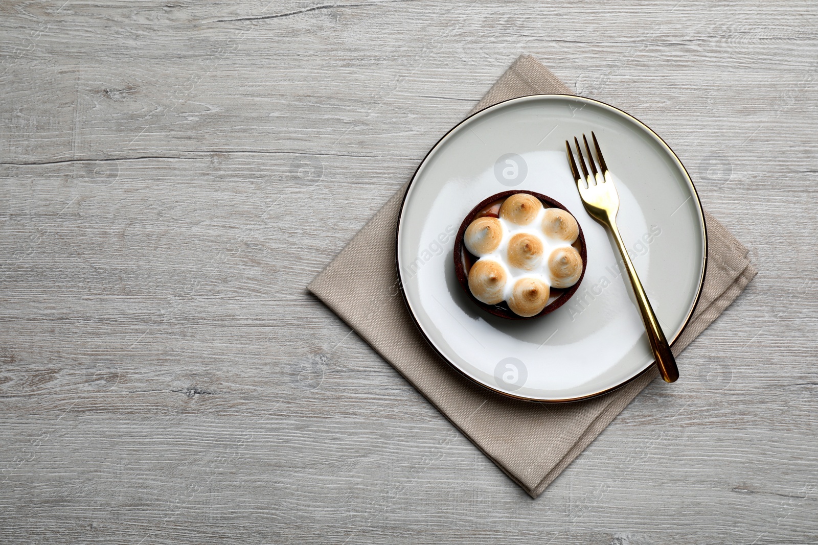 Photo of Delicious salted caramel chocolate tart with meringue served on light beige wooden table, top view. Space for text