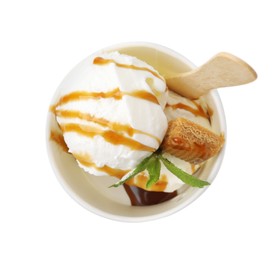 Photo of Tasty ice cream with caramel sauce, mint leaves and candy in paper cup isolated on white, top view