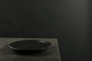 Photo of Beautiful ceramic plate on gray table against black background, space for text