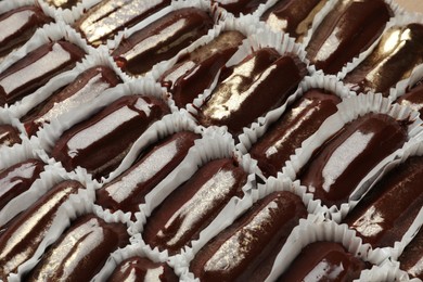 Many delicious eclairs with chocolate icing as background