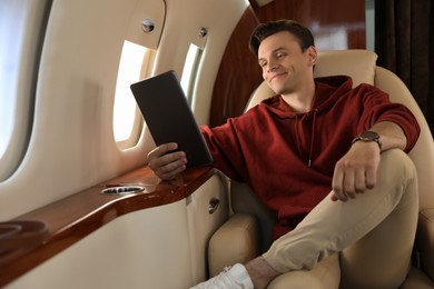 Photo of Young man using tablet in airplane during flight