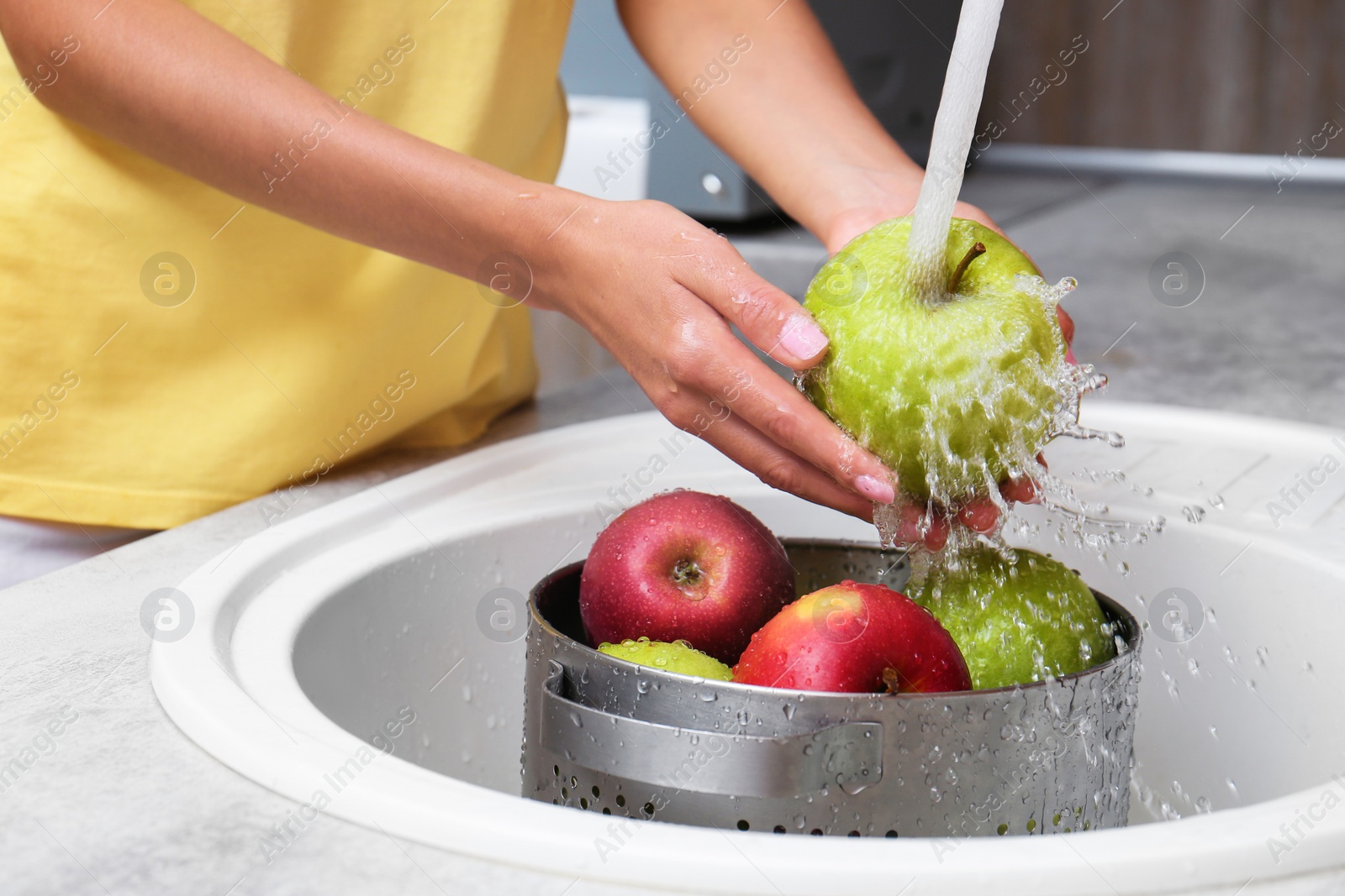 Photo of Woman washing fresh apples in kitchen sink, closeup