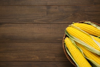 Photo of Tasty fresh corn cobs on wooden table, top view. Space for text