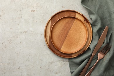 Photo of Stylish setting with cutlery, napkin and plates on light table, top view. Space for text