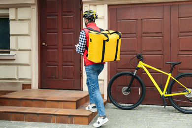 Courier with thermo bag and clipboard near customer's house. Food delivery service
