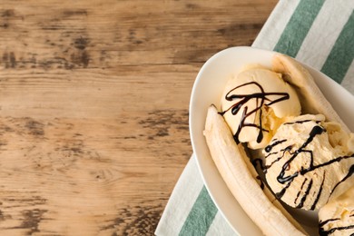 Delicious banana split ice cream with chocolate topping on wooden table, top view. Space for text