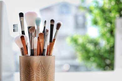 Holder with makeup brushes on table