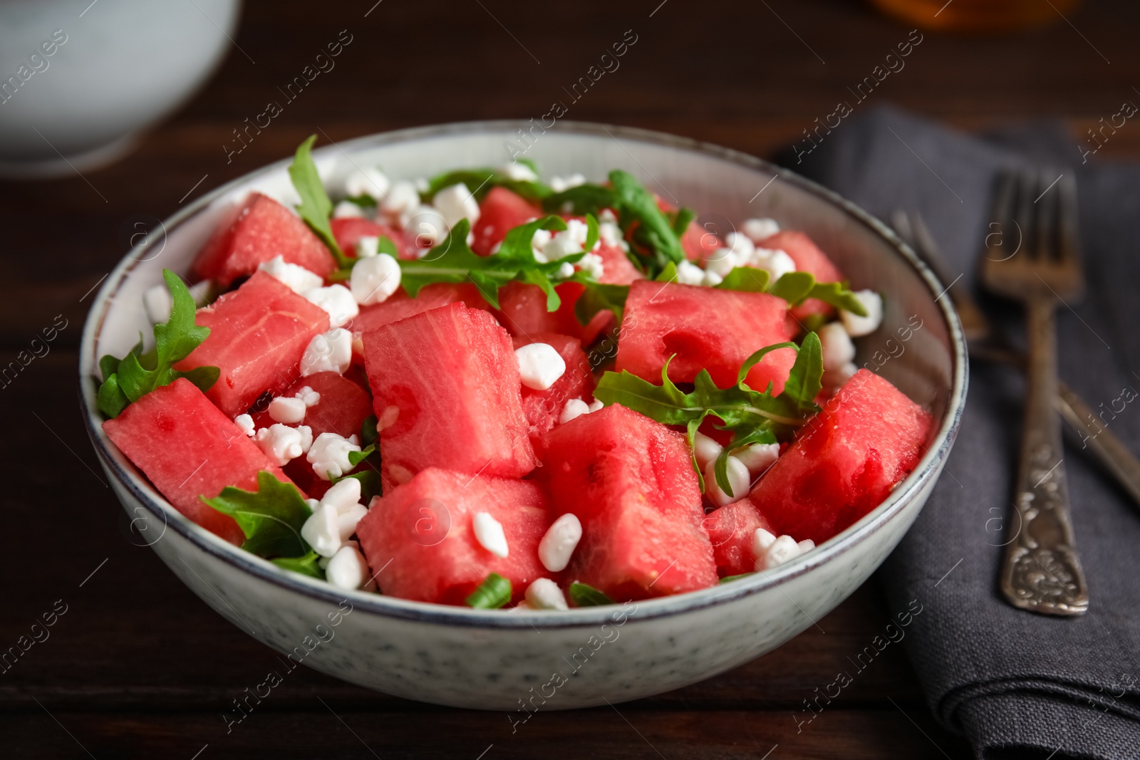 Photo of Delicious salad with watermelon, cheese and arugula on wooden table, closeup