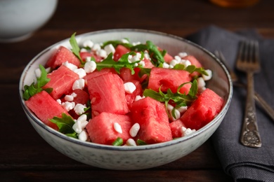 Photo of Delicious salad with watermelon, cheese and arugula on wooden table, closeup