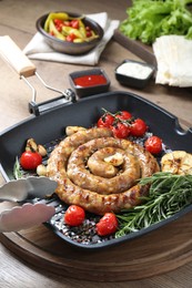 Photo of Delicious homemade sausage with garlic, tomatoes, rosemary and spices served on wooden table, closeup