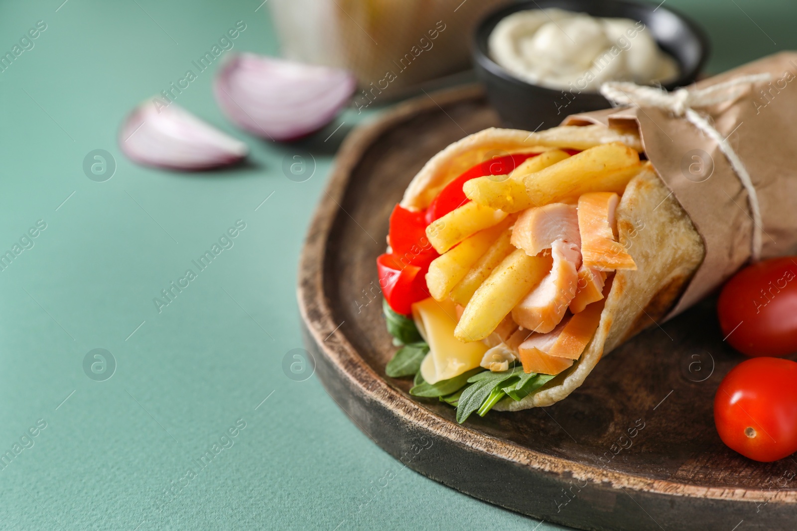 Photo of Delicious pita wrap with chicken, french fries and pepper on light blue background, closeup. Space for text
