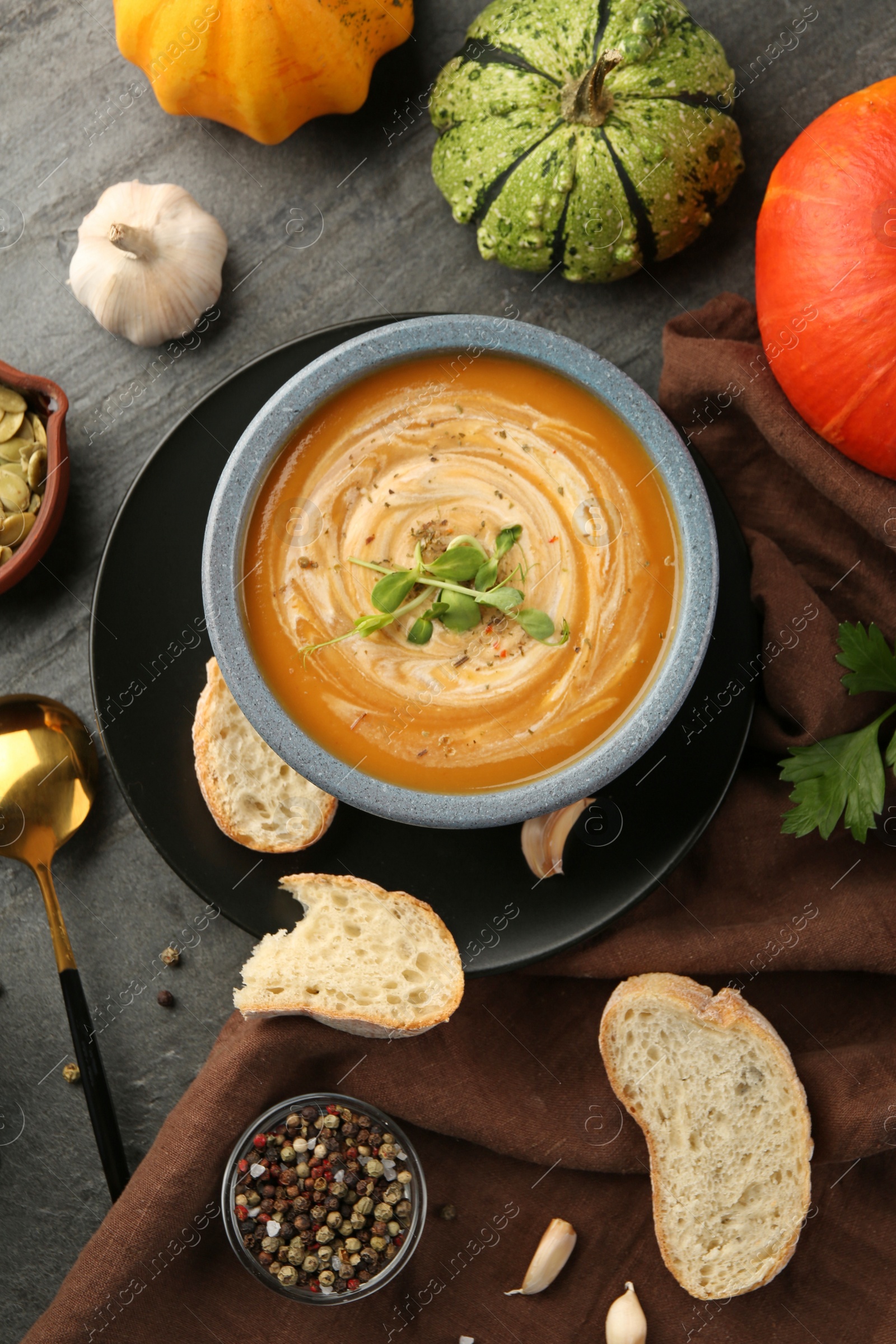 Photo of Flat lay composition with bowl of delicious pumpkin soup on grey textured table