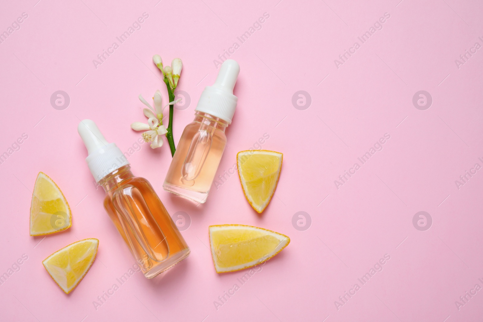 Photo of Flat lay composition with bottles of citrus essential oil on pink background. Space for text