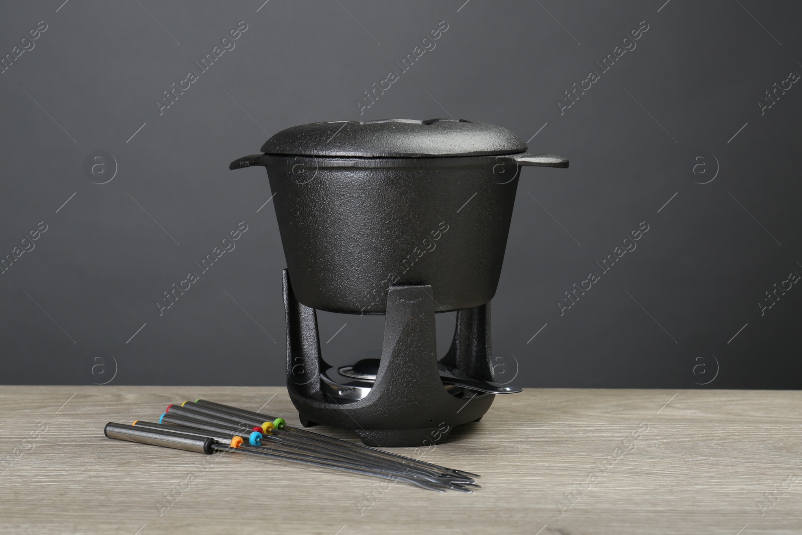 Photo of Fondue set on wooden table. Kitchen equipment