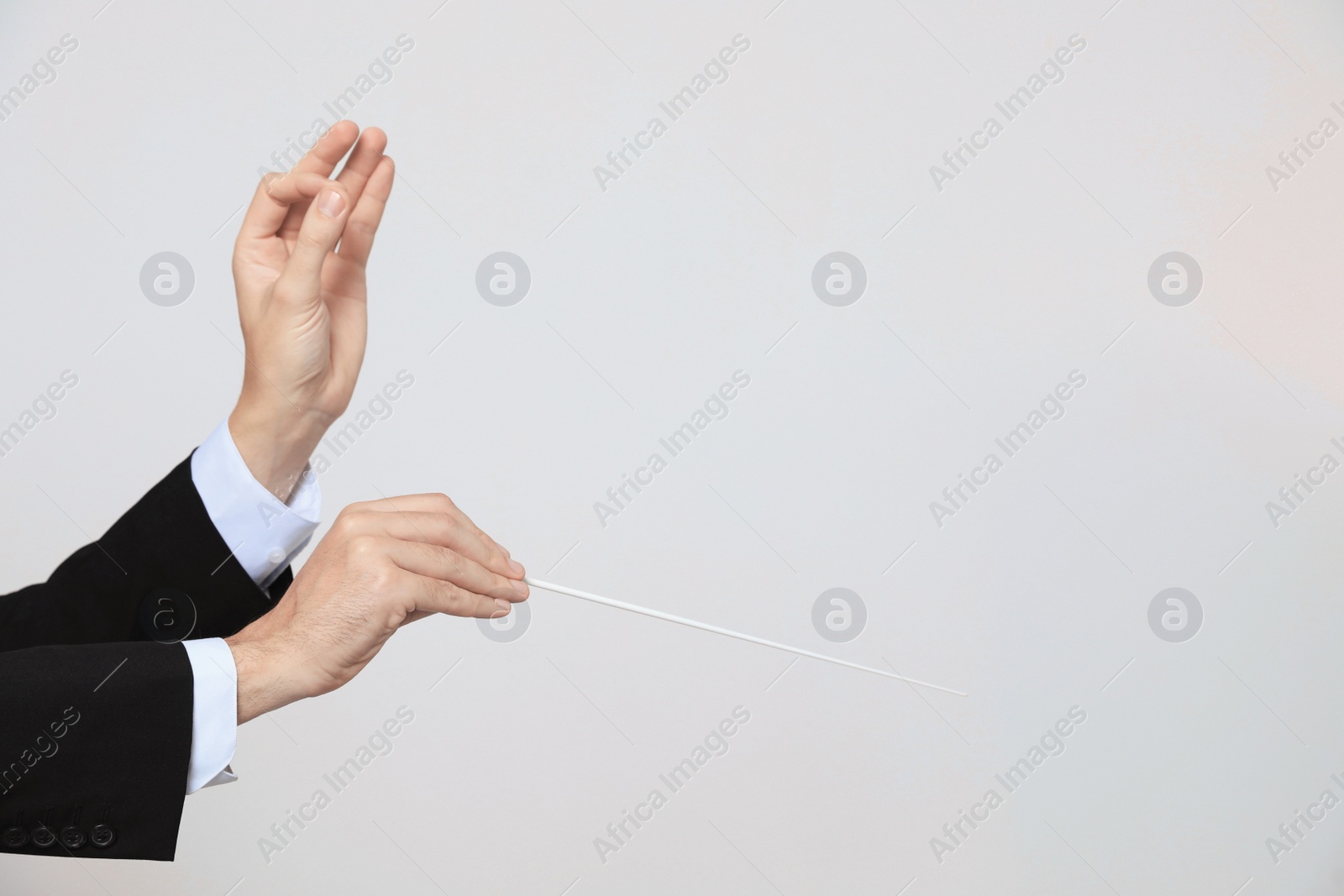 Photo of Professional conductor with baton on light grey background, closeup. Space for text