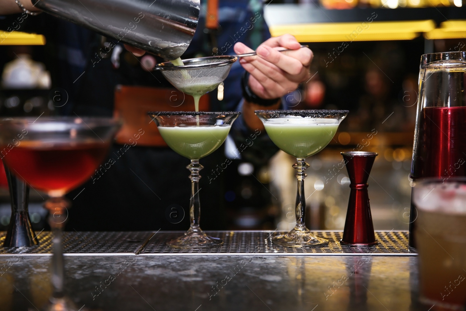 Photo of Bartender pouring tasty cocktail at counter in nightclub, closeup