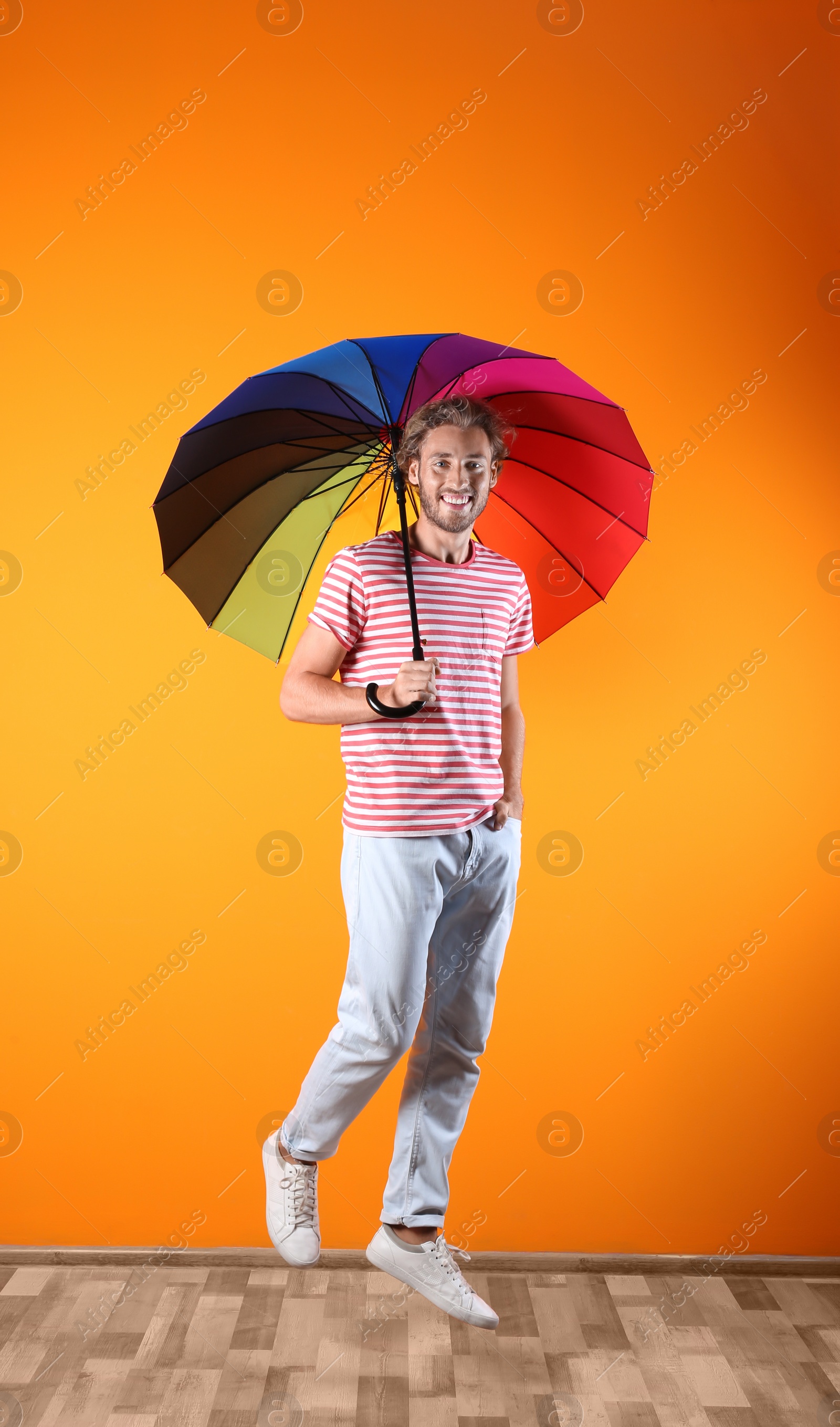 Photo of Man with rainbow umbrella near color wall