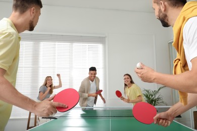 Happy friends playing ping pong together indoors