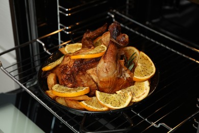 Baked chicken with orange slices and rosemary in oven