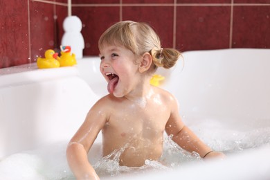 Happy girl having fun in bathtub at home