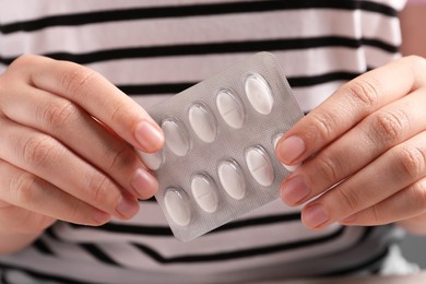 Woman holding blister of white pills, closeup