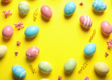 Photo of Frame made of painted Easter eggs on color background, space for text