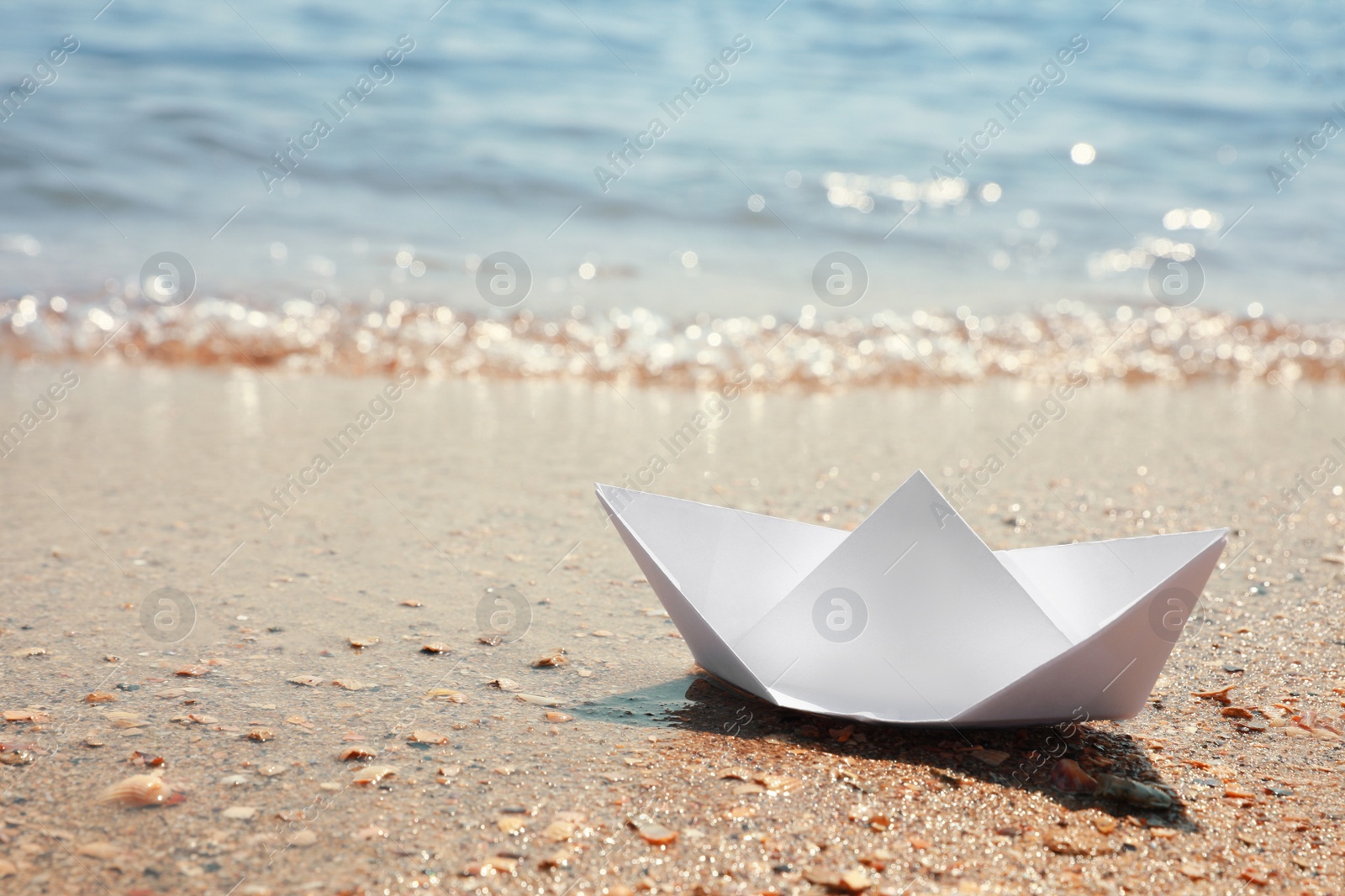 Photo of White paper boat near sea on sunny day, space for text