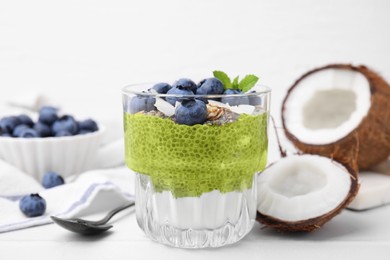Photo of Tasty matcha chia pudding with coconut and blueberries on white table, closeup. Healthy breakfast